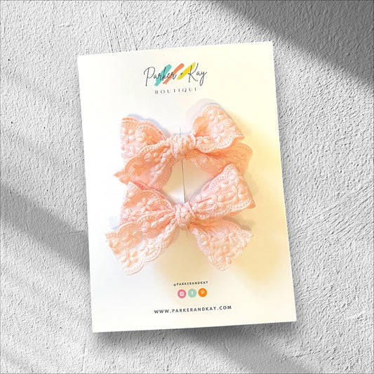 A set of two scalloped edge cotton hair bows with embroidered blooms in pink, presented on a Parker & Kay branded card