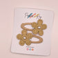Two golden yellow hair clips with embroidered flower details and pearl centers, displayed on a white branded card that reads Parker + Kay.