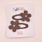 Two brown fabric flower hair clips with pearl centers, attached to a white display card branded Parker & Kay.