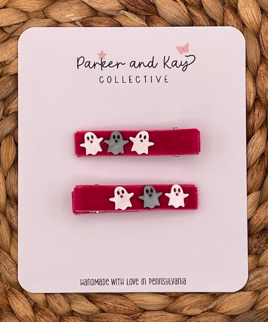 Two pink velvet hair clips with small white and gray ghost charms, displayed on a white branded card that reads 'Parker and Kay Collective' against a woven tan background.