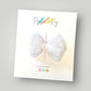 White tulle and velvet hair bow clip on a Parker & Kay branded card.